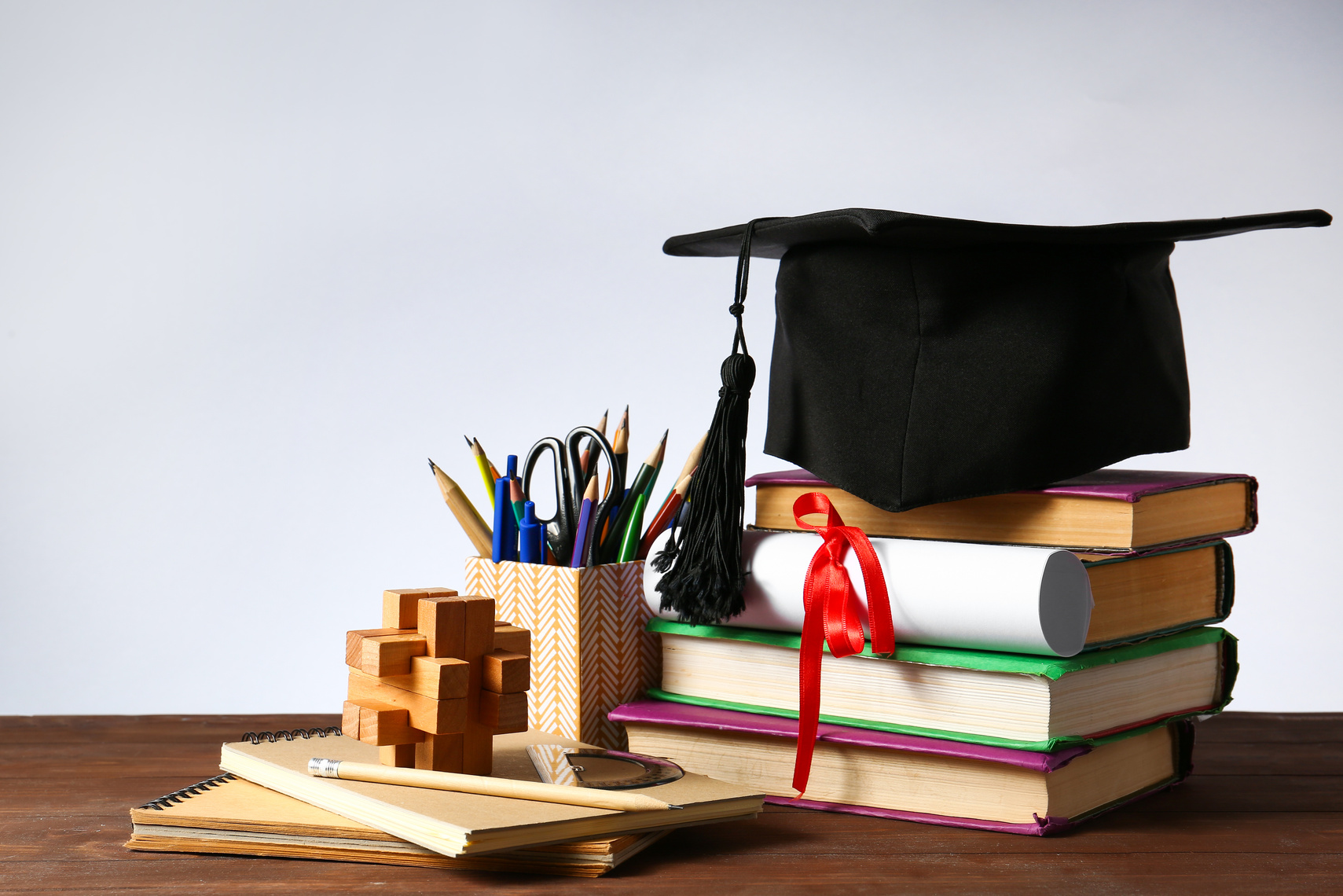 Mortar Board, Diploma, Stationery and Books on Table. Concept of High School Graduation