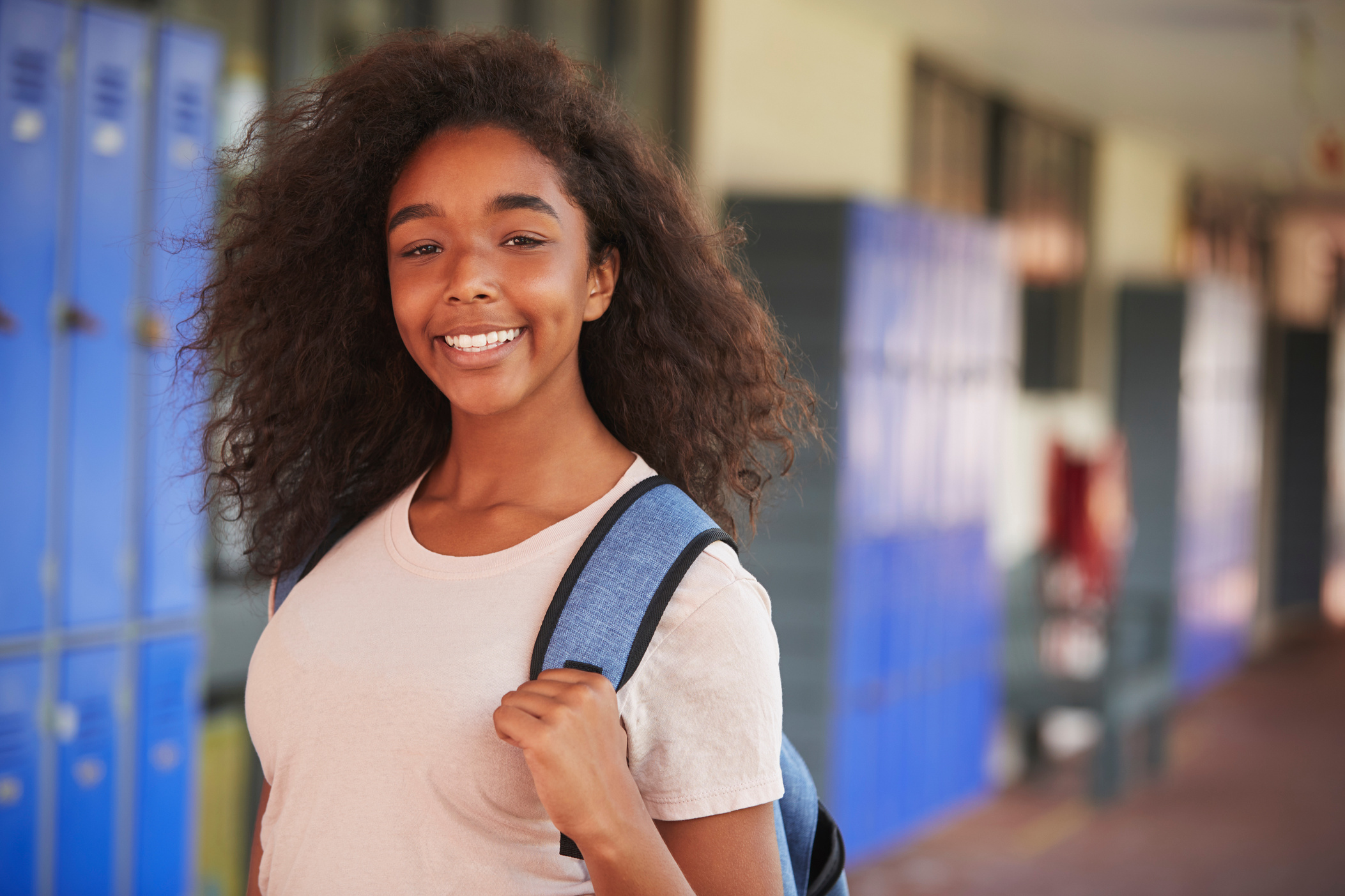 Happy Black Teenage Girl Smiling in High School Corridor